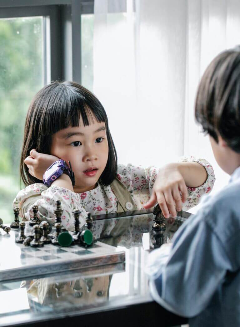 Pensive girl playing chess with brother